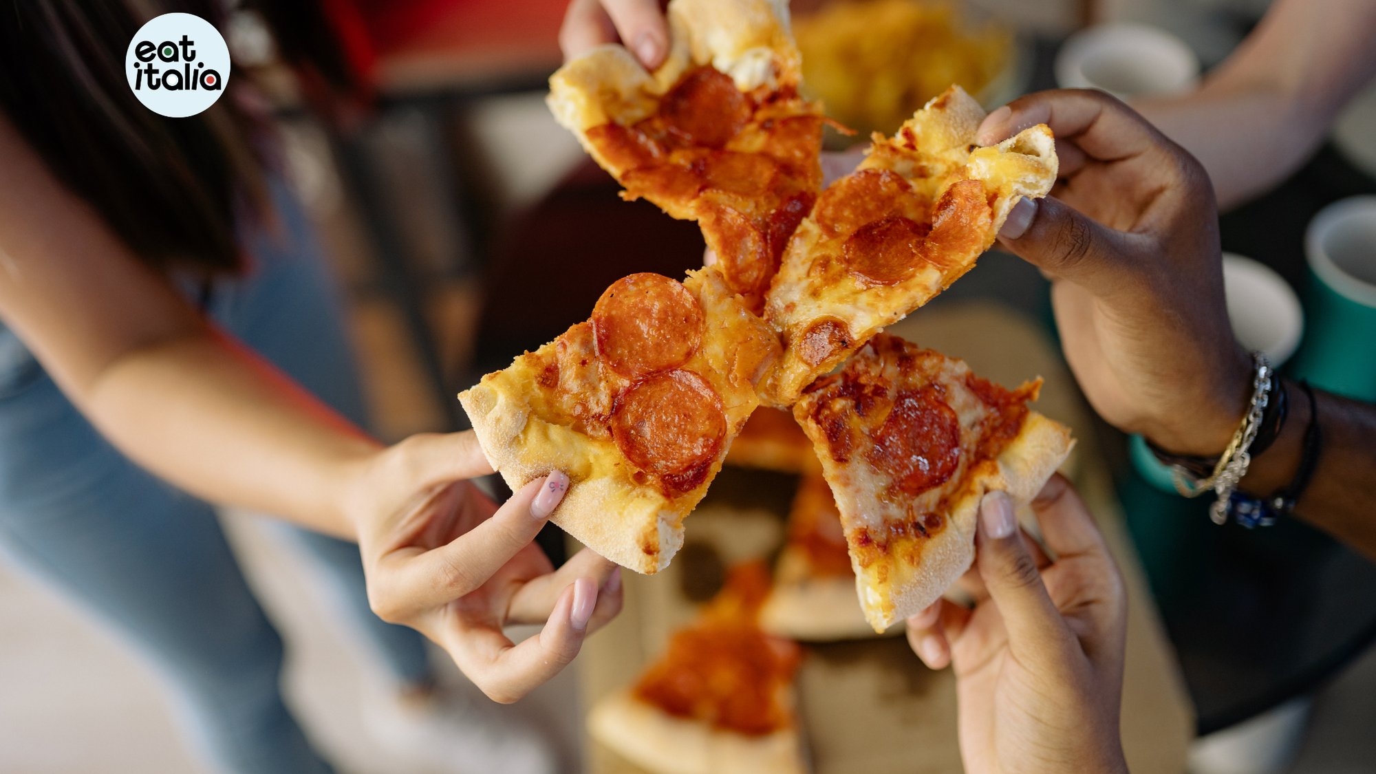 Four different hands handling a slice of cooked pizza each