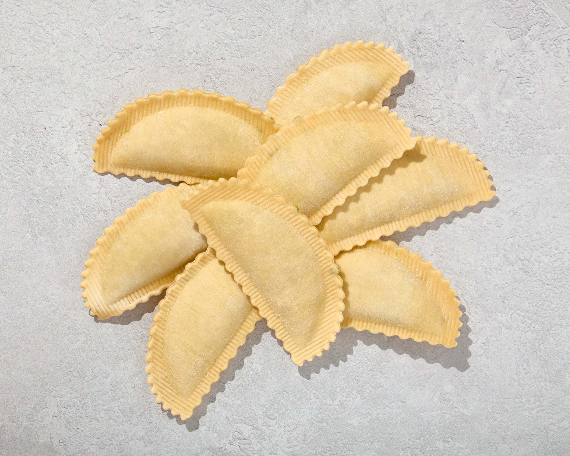 Uncooked agnolotti arranged on a light surface to show texture