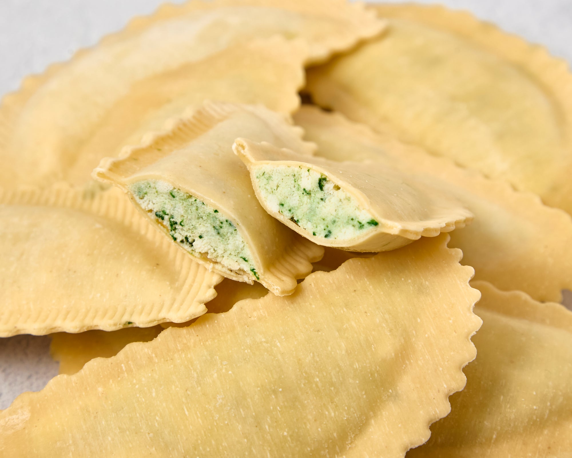 Cut agnolotti revealing spinach and ricotta filling
