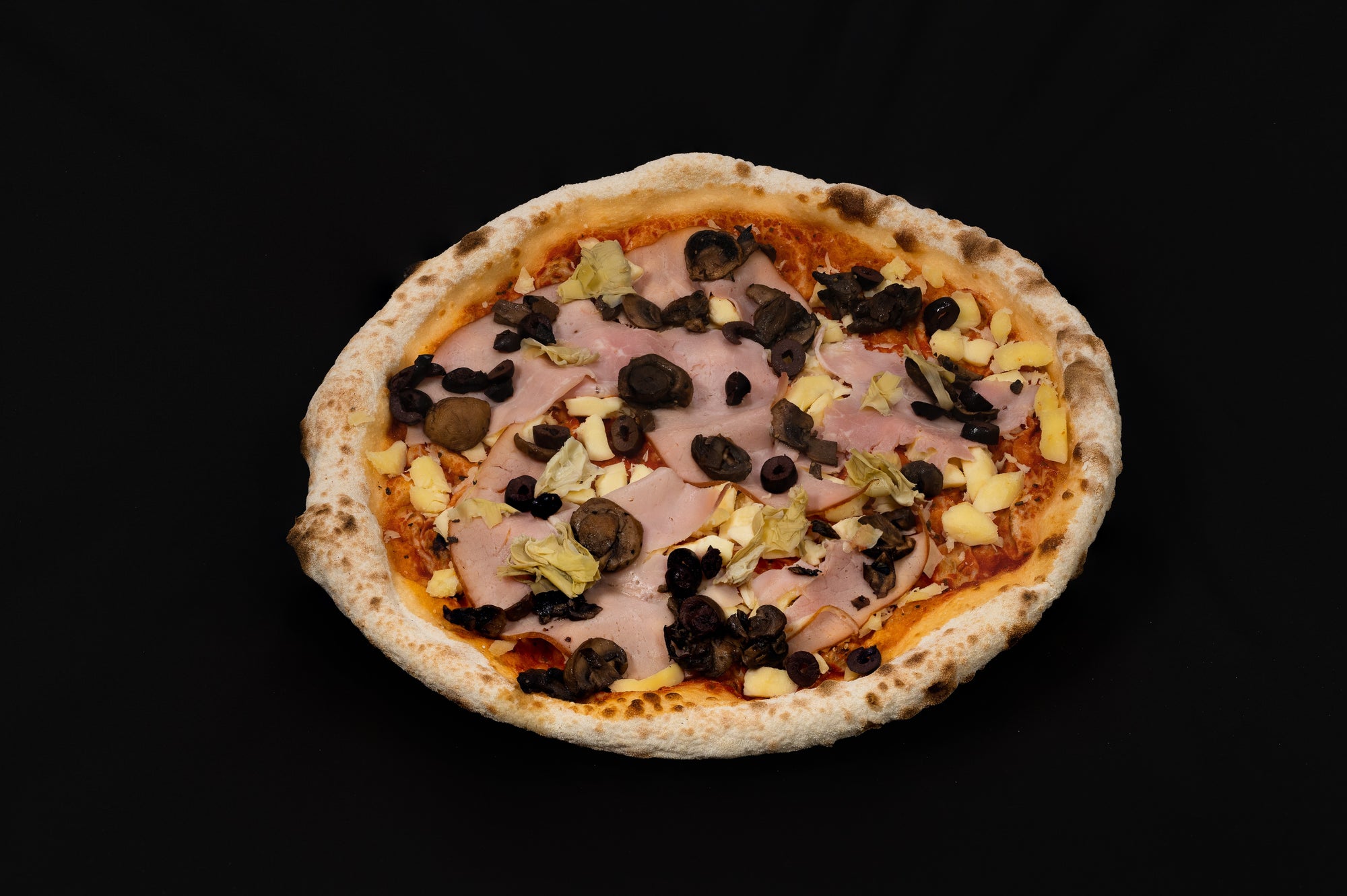 Single fresh pizza topped with mozzarella cheese, ham, mushrooms, black olives and artichokes, on a dark background.