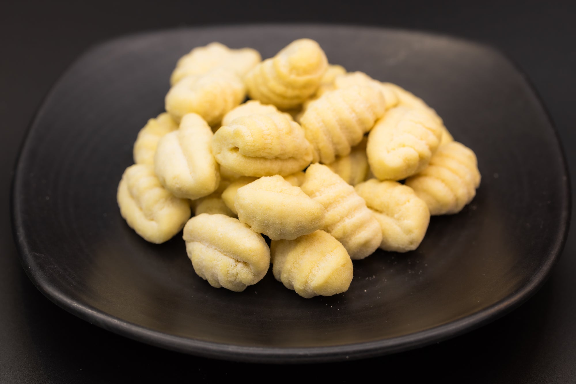 Uncooked gnocchi plain on a dark plate