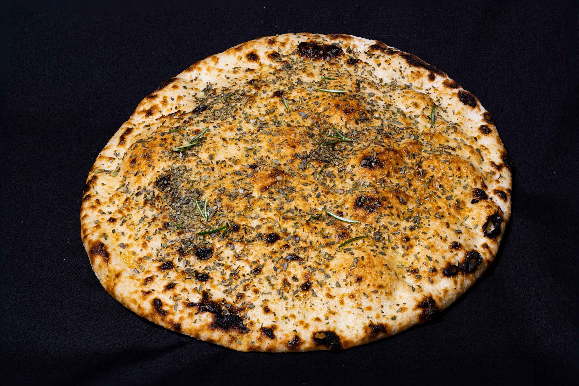 Close-up of plain pizza topped with garlic, oregano and rosematy