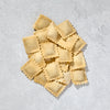 Fresh beef ravioli piled neatly on light background