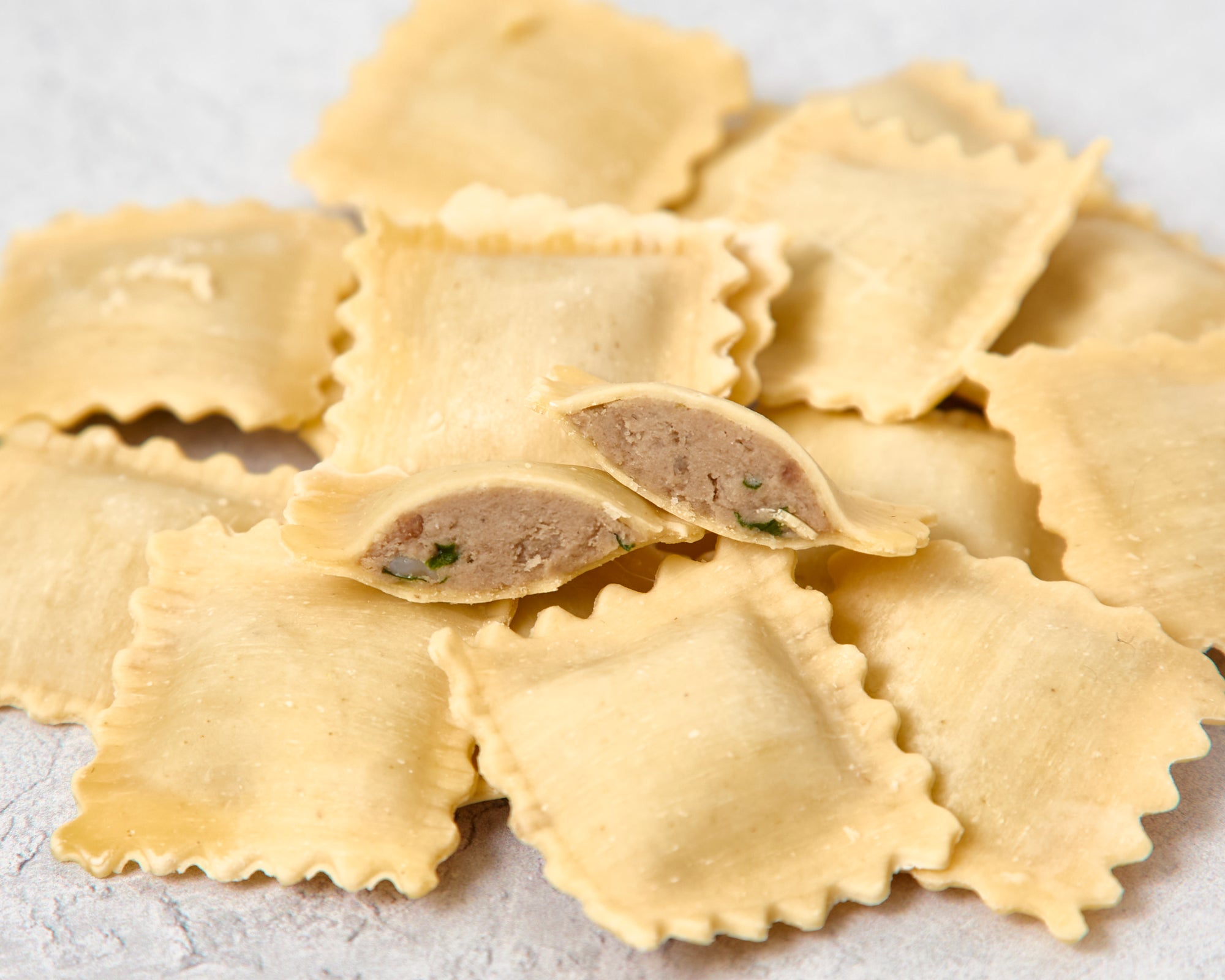 Uncooked cut ravioli showing beef filling