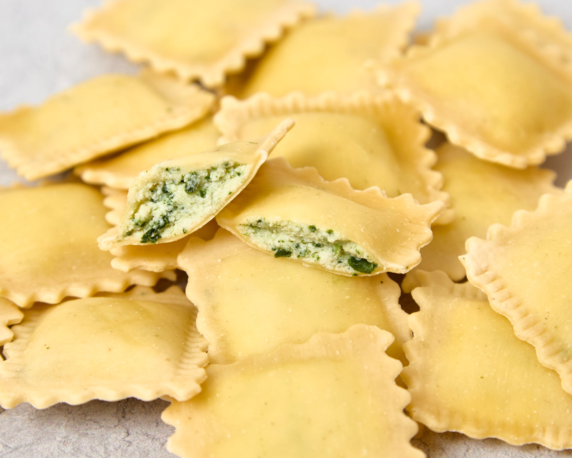 Close-up of ravioli cut open showing spinach and ricotta filling